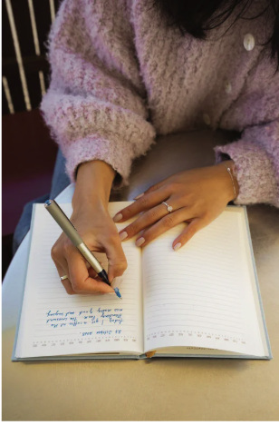 Hands writing in the Signature Program Summit workbook